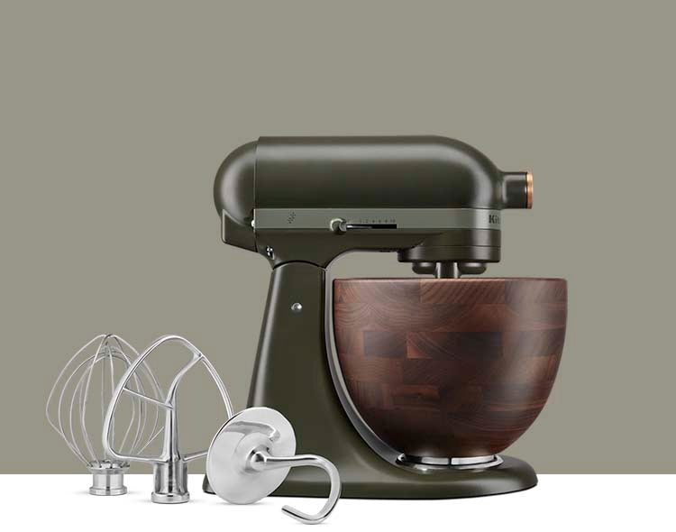 A KitchenAid tilt-head stand mixer in an Evergreen color with a wooden bowl and stainless steel attachments.
